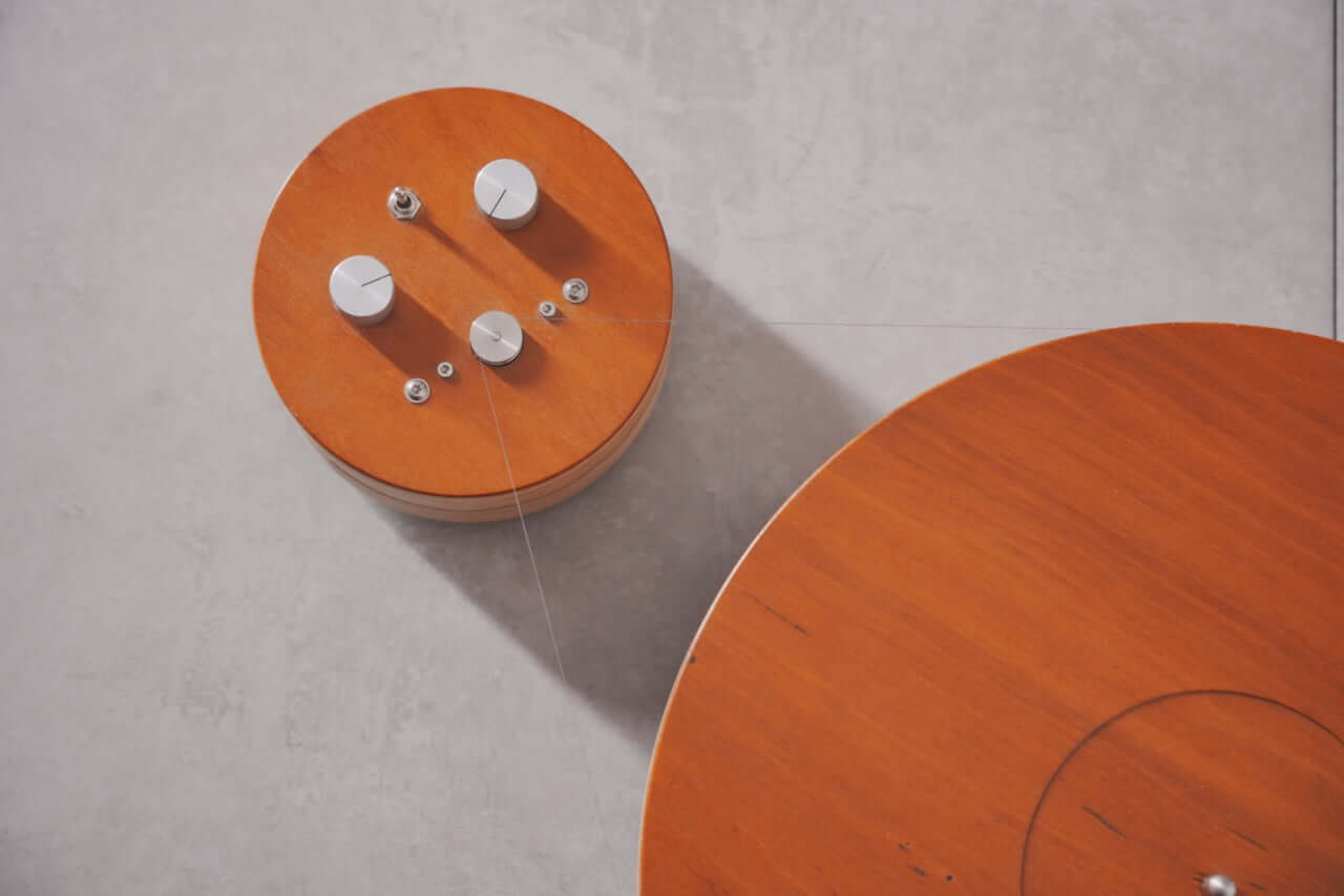 A close-up of the Arco 40 Plattenspieler—a wood turntable with metal knobs and visible wire—sits on a light gray surface, lit from above. Ideal for vinyl enthusiasts seeking retro vibes.