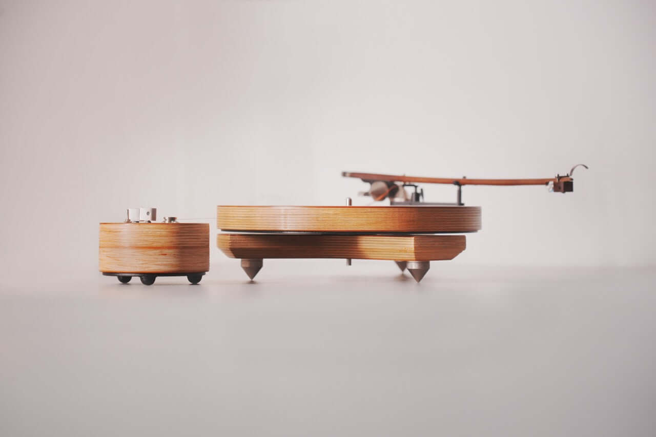 The Arco 40 Plattenspieler is a modern, minimalist wood turntable for vinyl, featuring a separate circular component, both displayed on a white surface with a plain white background.